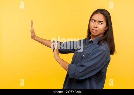 Nein, ich fürchte! Seitenansicht der Angst Mädchen in Denim-Shirt stehen mit erhobenen Händen Stop-Geste, Panik suchen Angst vor Gefahr, Phobie. indoo Stockfoto