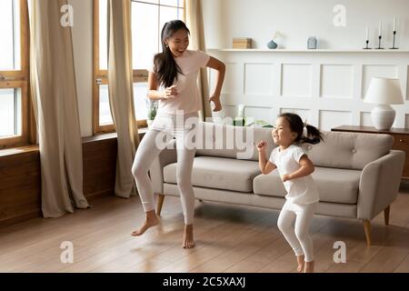 Energische junge vietnamesische ethnische Mutter tanzen mit Kind Tochter. Stockfoto