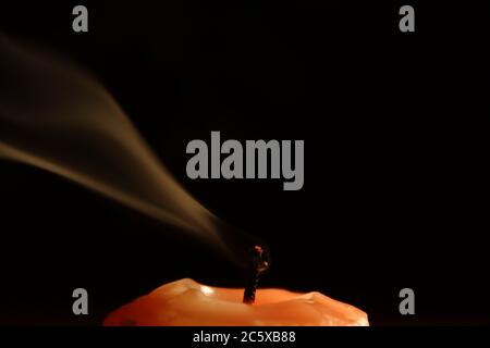 Erloschene orange Kerze auf einem dunklen Hintergrund mit Rauch Detail Stockfoto