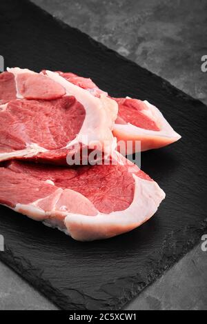 Zwei Stücke Schweinefleisch auf einem Schieferteller auf einem grauen Hintergrund. Kopierraum, Foto für Lebensmittelgeschäfte Stockfoto