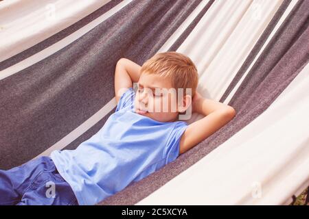 Vorschooljunge, der am Sommertag in einer Hängematte liegt Stockfoto