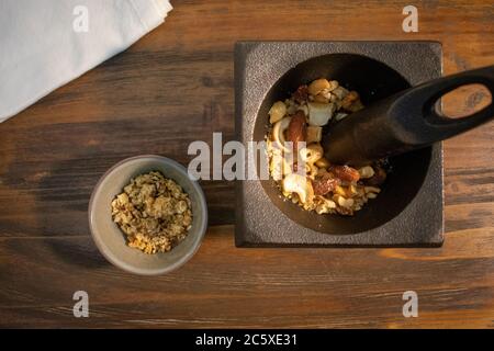 Gemischte Nüsse in Mörtel mit Stößel und Granola Schüssel mit Holzhintergrund Stockfoto