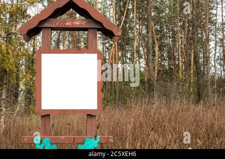 Weißes Quadrat in einem braunen Holzrahmen auf einem Waldhintergrund. Platz für Text, Banner, Mockup Stockfoto