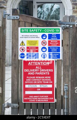 CV19, Covid-19 Schule Sicherheitsmassnahmen Warnschild & Warnpiktogramme am Tor der St. winnow Primary School, Lostwithiel, Cornwall. Stockfoto