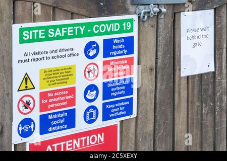CV19, Covid-19 Schule Sicherheitsmaßnahmen Warnschilder & Warnpiktogramme. Am Tor der St. winnow Primary School, Lostwithiel, Cornwall. Stockfoto
