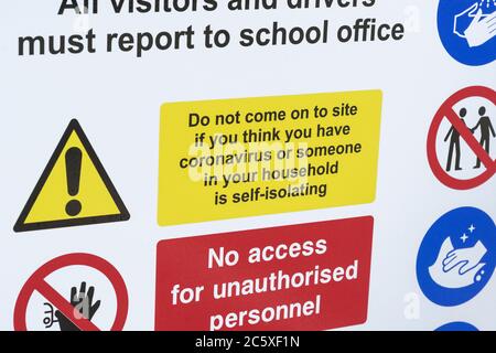 CV19, Covid-19 Schulsicherheitsmaßnahmen Warnschild & Warnpiktogramme am Tor der St. winnow Primary School, Lostwithiel. Selbstisolierendes Warnschild Stockfoto