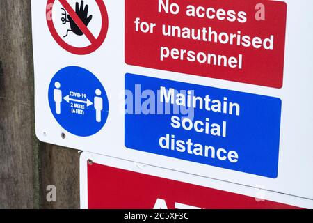 Covid-19 Schule Sicherheitsmassnahmen Warnschild & Warnpiktogramme am Tor der St. winnow Primary School, Lostwithiel. Sozialer Abstand Piktogramm. Stockfoto