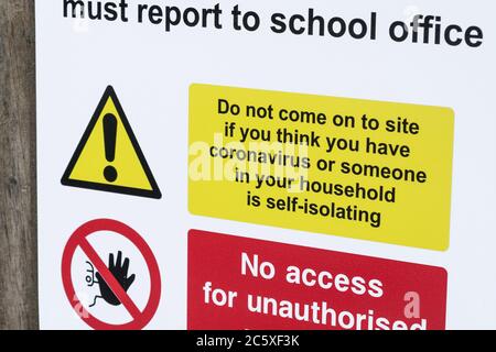 Covid-19 Schule Sicherheitsmaßnahmen Warnschilder & Warnpiktogramme. Am Tor der St. winnow Grundschule, Lostwihiel. Selbstisolierendes Warnschild. Stockfoto