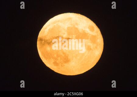 Highcliffe, Dorset, Großbritannien. Juli 2020. Wetter in Großbritannien. Der volle Buck Moon leuchtet orange, als eine wispy Wolke vor ihm vorbeizieht, von Highcliffe in Dorset kurz nach dem Mondaufgang betrachtet. Bildquelle: Graham Hunt/Alamy Live News Stockfoto