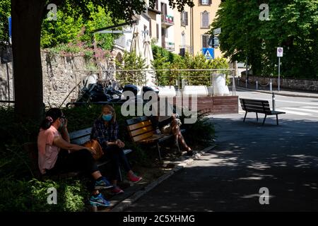 An einem lauwarmen Tag entspannen sich die Menschen draußen auf Bänken, während sie sich unterhalten und Zeitung lesen in der Gegend namens 'Colle aperto'. Città alta. Stockfoto