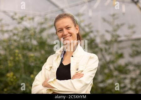 Junge Frau, die als Gemüseanbauer oder Landwirt in einem steht Gewächshaus Stockfoto