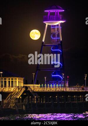 Bournemouth, Großbritannien. Juli 2020. Der Juli-Vollmond, auch bekannt als Buck Moon, steigt über Bournemouth Pier an der Dorset-Küste auf. Kredit: Richard Crease/Alamy Live Nachrichten Stockfoto