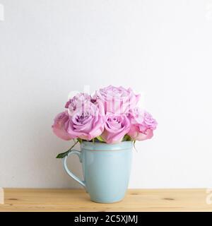 Lila Rose Blumen in Tasse auf Holztisch mit weißem Hintergrund. Copy Space Stockfoto