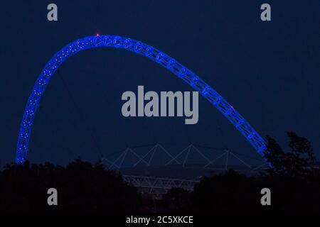 Wembley, Großbritannien. Juli 2020. Wetter in Großbritannien - der Bogen des Wembley-Stadions ist blau beleuchtet, um den 72. Geburtstag des National Health Service (NHS) zu feiern und allen NHS-Mitarbeitern für ihre Bemühungen während der laufenden Coronavirus-Pandemie zu danken. Der Vollmond des Juli, bekannt als Buck Moon, wird sich hinter dem Wembley Stadium im Nordwesten Londons erheben. Im Bauernalmanach ist der Buck Moon so benannt nach dem neuen Geweih, das um diese Jahreszeit aus der Stirn eines Bocks hervortritt. Kredit: Stephen Chung / Alamy Live Nachrichten Stockfoto