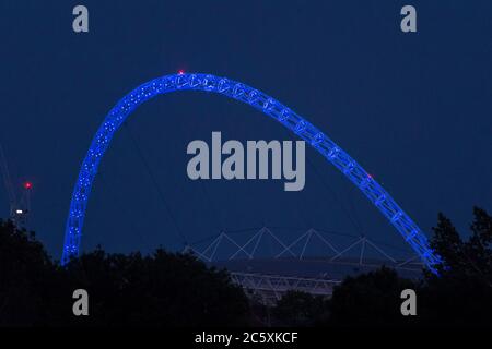 Wembley, Großbritannien. Juli 2020. Wetter in Großbritannien - der Bogen des Wembley-Stadions ist blau beleuchtet, um den 72. Geburtstag des National Health Service (NHS) zu feiern und allen NHS-Mitarbeitern für ihre Bemühungen während der laufenden Coronavirus-Pandemie zu danken. Der Vollmond des Juli, bekannt als Buck Moon, wird sich hinter dem Wembley Stadium im Nordwesten Londons erheben. Im Bauernalmanach ist der Buck Moon so benannt nach dem neuen Geweih, das um diese Jahreszeit aus der Stirn eines Bocks hervortritt. Kredit: Stephen Chung / Alamy Live Nachrichten Stockfoto