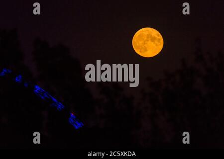 Wembley, Großbritannien. Juli 2020. UK Wetter - der Vollmond des Juli, bekannt als Buck Moon, erhebt sich hinter dem Wembley Stadium im Nordwesten Londons. Im Bauernalmanach ist der Buck Moon so benannt nach dem neuen Geweih, das um diese Jahreszeit aus der Stirn eines Bocks hervortritt. Der Bogen des Stadions ist blau beleuchtet, um den 72. Geburtstag des National Health Service (NHS) zu feiern und allen NHS-Mitarbeitern für ihre Bemühungen während der laufenden Coronavirus-Pandemie zu danken. Kredit: Stephen Chung / Alamy Live Nachrichten Stockfoto