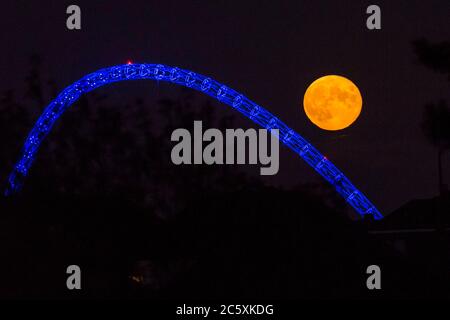 Wembley, Großbritannien. Juli 2020. UK Wetter - der Vollmond des Juli, bekannt als Buck Moon, erhebt sich hinter dem Wembley Stadium im Nordwesten Londons. Im Bauernalmanach ist der Buck Moon so benannt nach dem neuen Geweih, das um diese Jahreszeit aus der Stirn eines Bocks hervortritt. Der Bogen des Stadions ist blau beleuchtet, um den 72. Geburtstag des National Health Service (NHS) zu feiern und allen NHS-Mitarbeitern für ihre Bemühungen während der laufenden Coronavirus-Pandemie zu danken. Kredit: Stephen Chung / Alamy Live Nachrichten Stockfoto