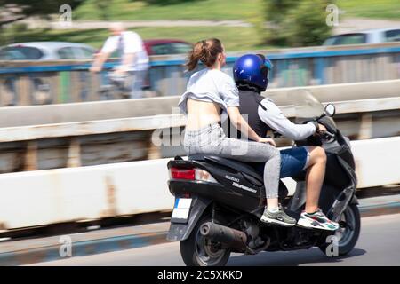 Belgrad, Serbien - 4. Juli 2020: Junge Männer und Frauen ohne Helm auf der Stadtbrücke auf dem Roller reiten Stockfoto