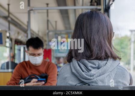 Weibliche Fahrgast sitzen im Zug mit abgesetzten Hintergrund der asiatischen männlichen Fahrgast tragen Gesichtsschutz Maske während der Epidemie von COVID-19. Stockfoto