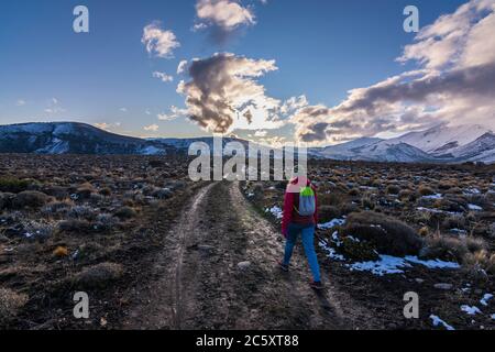 Szenenansicht einer Frau, die im Winter auf einem launischen Pfad gegen schneebedeckte Berge wandert, Esquel, Patagonien, Argentinien Stockfoto