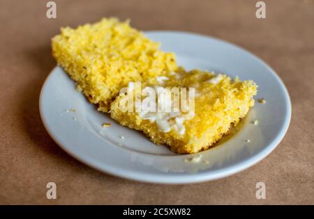 Ein Stück goldenes, warmes Maisbrot, wird gespalten und mit schmelzender Cremesumbutter bedeckt Stockfoto