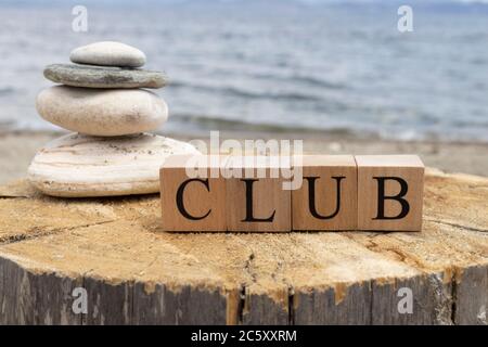 Das Wort Club aus Holzwürfeln. Die Würfel sind auf dem Baumstumpf. Stockfoto