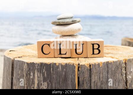 Das Wort Club aus Holzwürfeln. Die Würfel sind auf dem Baumstumpf. Stockfoto