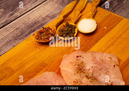 Fleischsteaks und verschiedene Gewürze auf einem Holzbrett. Nahaufnahme Stockfoto