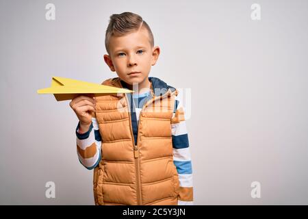 Junge kleine kaukasische Kind Spaß und spielen Phantasie fliegen mit Papier Flugzeug mit einem selbstbewussten Ausdruck auf intelligente Gesicht denken ernst Stockfoto