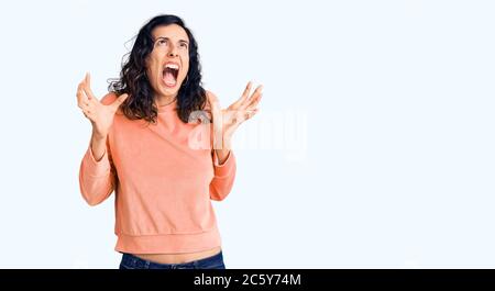 Junge schöne hispanische Frau in Freizeitkleidung verrückt und verrückt schreien und schreien mit aggressiven Ausdruck und Arme angehoben. Frustration conce Stockfoto