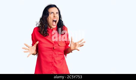 Junge schöne hispanische Frau in Freizeitkleidung verrückt und verrückt schreien und schreien mit aggressiven Ausdruck und Arme angehoben. Frustration conce Stockfoto
