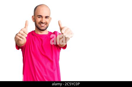 Junger schöner Mann trägt Casual T-Shirt Genehmigung tun positive Geste mit der Hand, Daumen hoch lächelnd und glücklich für den Erfolg. Sieger Geste. Stockfoto