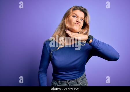 Junge schöne blonde Frau trägt Casual T-Shirt über isolierten lila Hintergrund schneiden Kehle mit Hand als Messer, drohen Aggression mit furiou Stockfoto