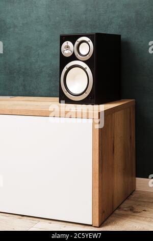 Eine moderne schwarz Audio Lautsprecher System im Innenbereich auf Holz Schreibtisch in der Nähe des dunklen grünen Wand Stockfoto