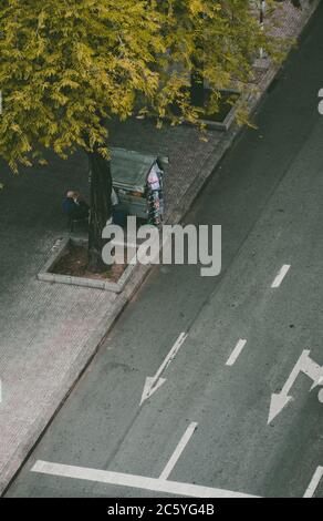 Saigon, Vietnam - 4. Juli 2020: Die Straßen von Saigon (Ho Chi Min City), Ansicht von oben auf einer Frau, die an einem Zigarettenwagen auf dem Bürgersteig sitzt Stockfoto