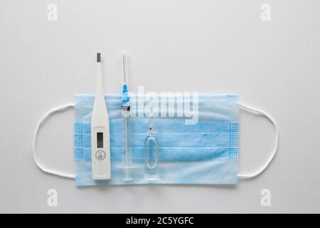 Medizinische Maske auf schwarzem Hintergrund.Gesichtsmaske. Maske für Krankheiten. Thermometer und Medikation. Das Bild einer einzelnen Person. Verband der medizinischen Atmung im Gesicht. Das Konzept des Quarantäne-Coronavirus Stockfoto