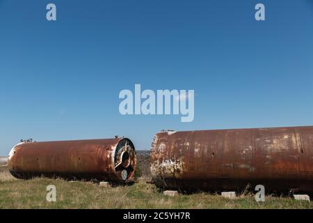 Zwei alte verlassene rostige Fässer liegen im Freien auf dem Gras. Stockfoto