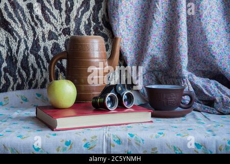 Stillleben mit einem Apfel, einer Tasse, einem Krug, einem Fernglas und einem Buch. Bildmaterial zum Zeichnen Stockfoto