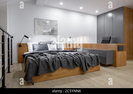 Stilvolles und neues Design-Schlafzimmer mit großem Holzbett, langem Holzschreibtisch und Holzschrank Stockfoto