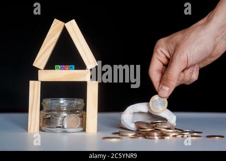 Risiko, Geld in Immobilienprojekte zu investieren, konzeptuelles Image mit Hausform aus Holzblöcken und Cash Money auf weißem Hintergrund Stockfoto
