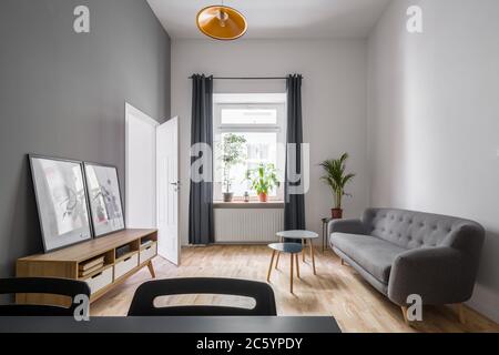 Gemütliches Zimmer in Grau und Weiß mit Holzgehäuse und einfache Couch Stockfoto