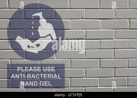 Weiß verfaulte Backstein Wand Hintergrund mit bitte antibakterielle Hand Gel Zeichen verwenden, um die Ausbreitung der weltweiten Pandemie zu stoppen Stockfoto