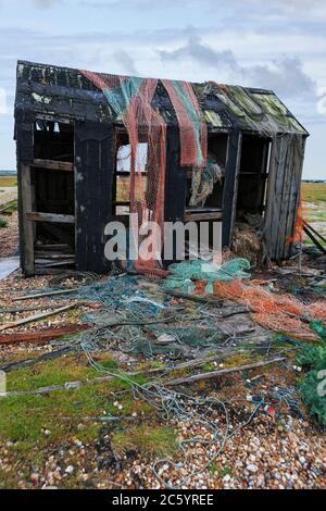 Alte verfallene Fischerhütte mit verlassenen Fischernetzen, am Dungeness Beach, Kent, England, UK Stockfoto