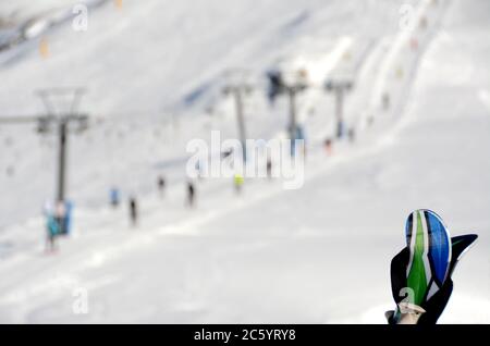 Skiausrüstung auf verschwommenem Hintergrund von Skifahrern, Schnee, Pisten, Skilift in der alpinen Sonne des Piemont. Stockfoto