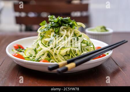 Nudeln mit spiralförmigen Zucchini, Gurke, Kirschtomate, Knoblauch in einem cremigen Pesto aus Avocado. Rohkost für Vegetarier. Nahaufnahme Stockfoto