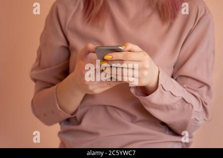 Fröhliche junge Frau schreibt eine SMS mit ihrem Handy. Hübsche junge Frau mit Smartphone. Junge Hipster halten Handy und Blick auf Th Stockfoto