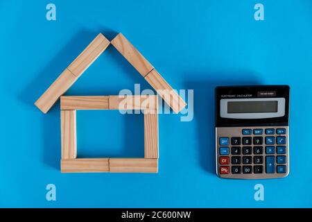 Nahaufnahme des Holzmodells und der Schlüssel mit Taschenrechner auf blauem Hintergrund. Hypothek Immobilien Versicherung kaufen Traum Haus Shopping Verkauf Miete Konzept. Wohnung lag Stockfoto