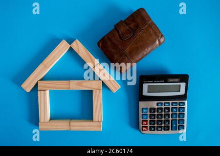 Nahaufnahme des Holzmodells und der Schlüssel mit Taschenrechner auf blauem Hintergrund. Hypothek Immobilien Versicherung kaufen Traum Haus Shopping Verkauf Miete Konzept. Wohnung lag Stockfoto