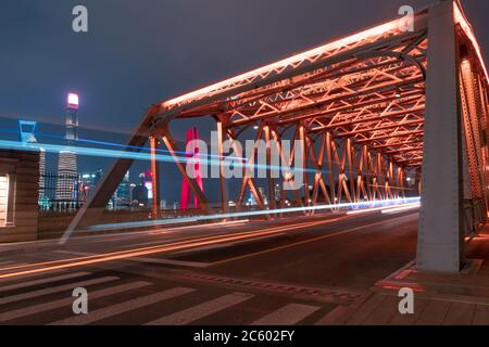 Nachtansicht der Waibaidu Bridge, einer der Wahrzeichen von Shanghai, mit Verkehr und modernen Wolkenkratzern im Hintergrund. Stockfoto