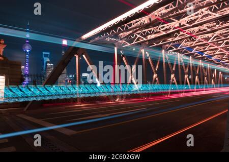 Nachtansicht der Waibaidu Bridge, einer der Wahrzeichen von Shanghai, mit Verkehr und modernen Wolkenkratzern im Hintergrund. Stockfoto